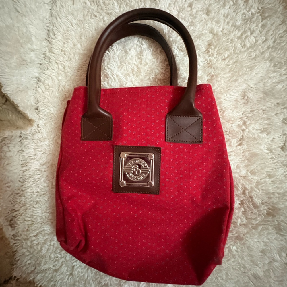 Scented Dreams red patterned canvas with brown leather handles.
